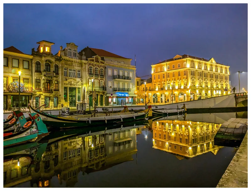 Historic buildings and boats along a canal at night, with reflections in the water.