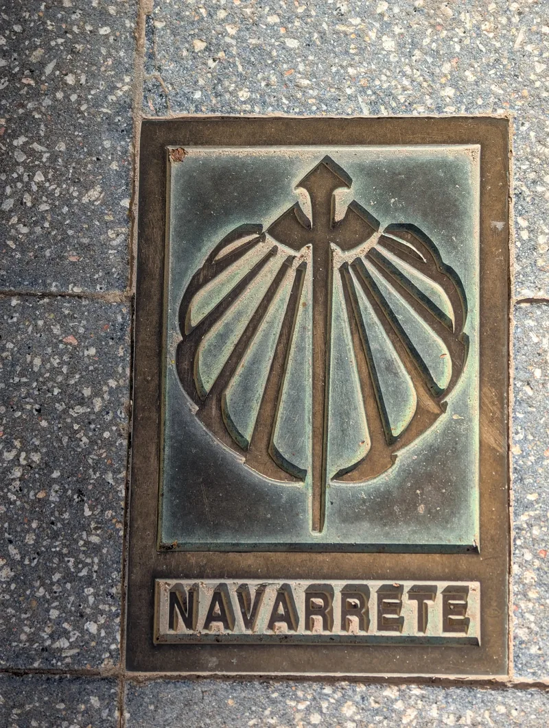 Bronze plaque on pavement featuring a scallop shell design and the word "NAVARRETE.